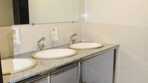 Une salle de bain avec deux lavabos, un miroir et un panneau indiquant qu'il est interdit de fumer.