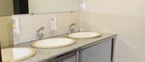 A bathroom with two sinks, a mirror, and a no-smoking sign.