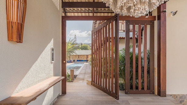 A corridor leading to a pool area with a wooden bench and a decorative ceiling. - Kite Star Cumbuco By Carpediem (Caucaia)