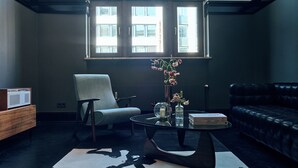 Een moderne woonkamer met een groot boogvenster, een bijzondere kroonluchter en een leren bank.