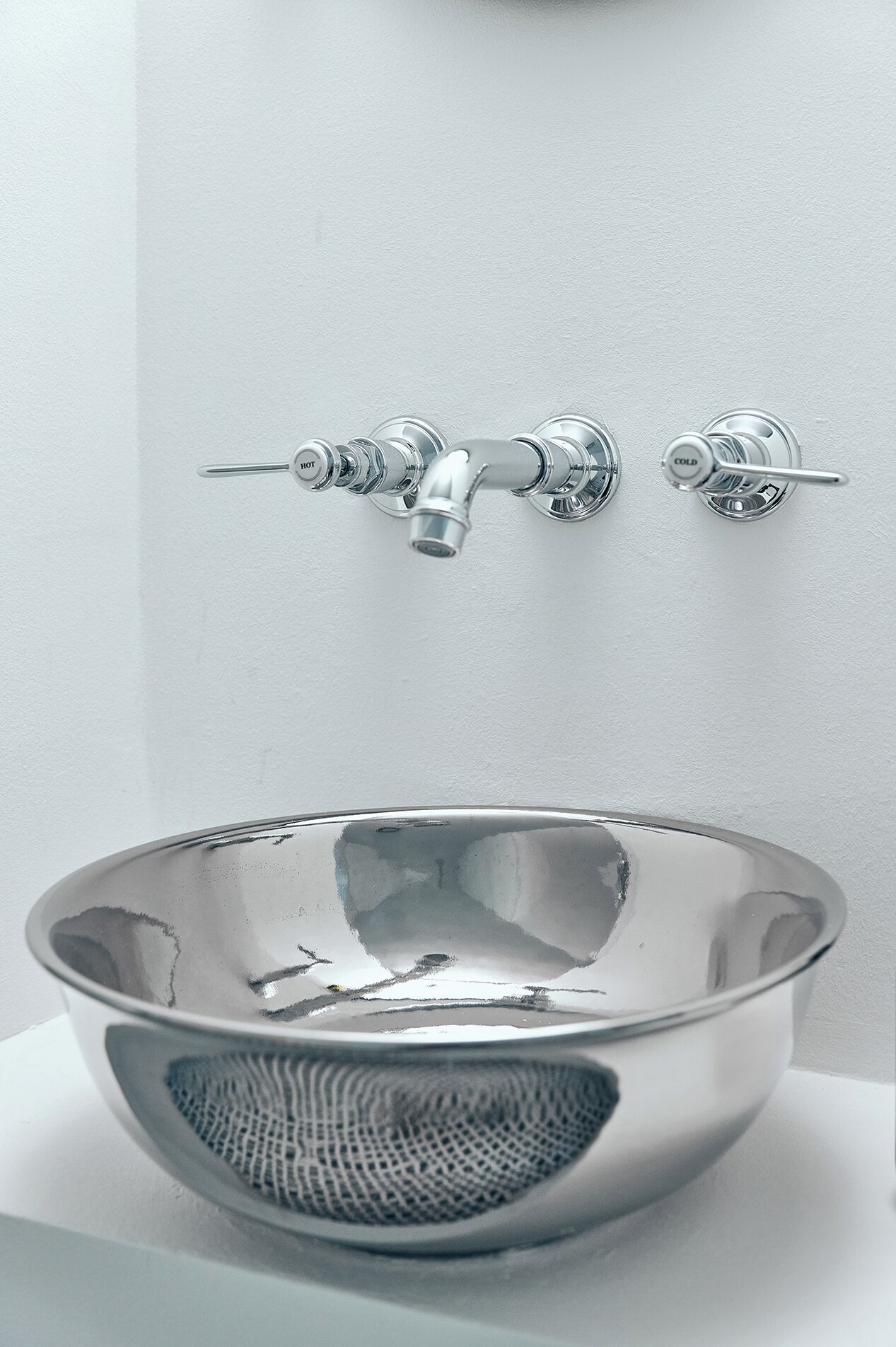 Een moderne badkamer met een chromen kraan, een glazen wasbak en een reliëf zeef.