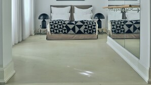 Een slaapkamer met een bed, nachtkastjes, een spiegel en ingelijste foto’s aan de muur.