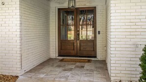 A white brick exterior with a double wooden door and a hanging lantern.