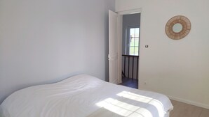 Une chambre avec un lit, une porte donnant sur un balcon et un miroir fixé au mur.
