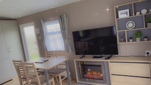 Ein gemütlicher Wohnbereich mit Fernseher, Kamin, Esstisch und Stühlen.