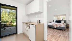 Une cuisine moderne équipée d’un four à micro-ondes encastré, d’un petit réfrigérateur et d’une bouilloire posée sur le plan de travail.