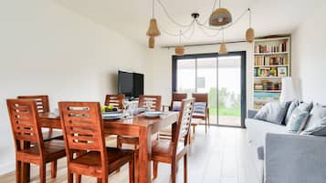 A dining area with a wooden table and chairs, a television, and a bookshelf.