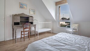 A bedroom with a wooden desk, a white bed, a window, and a chair. - 50m from the beach, house with garden for 10 (Piriac-sur-Mer)