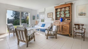 A spacious living room with a sofa, chairs, a coffee table, and a wooden cabinet with decorative plates. - 50m from the beach, house with garden for 10 (Piriac-sur-Mer)