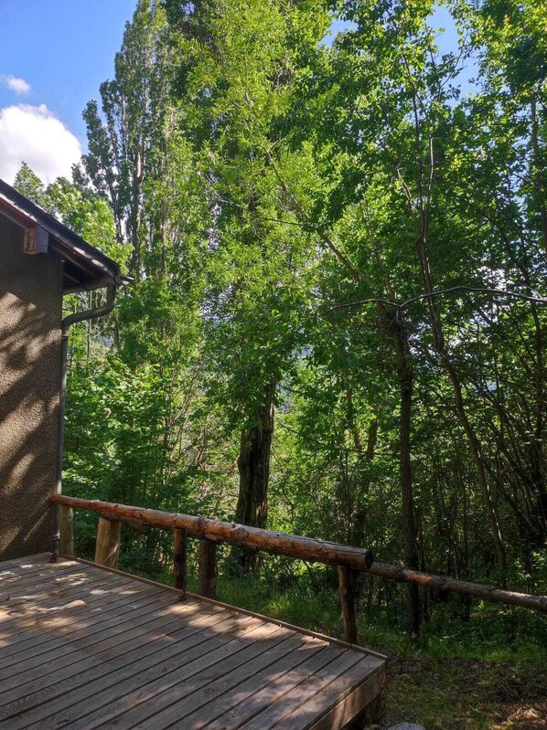 A wooden deck with a railing overlooking a forested area. - Forest house in the heart of nature in Llo - Pyrénées Cerdagne (Llo)