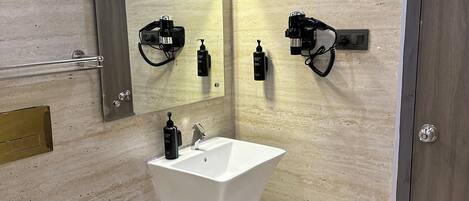 A modern bathroom with a white sink, a mirror, and a toilet.