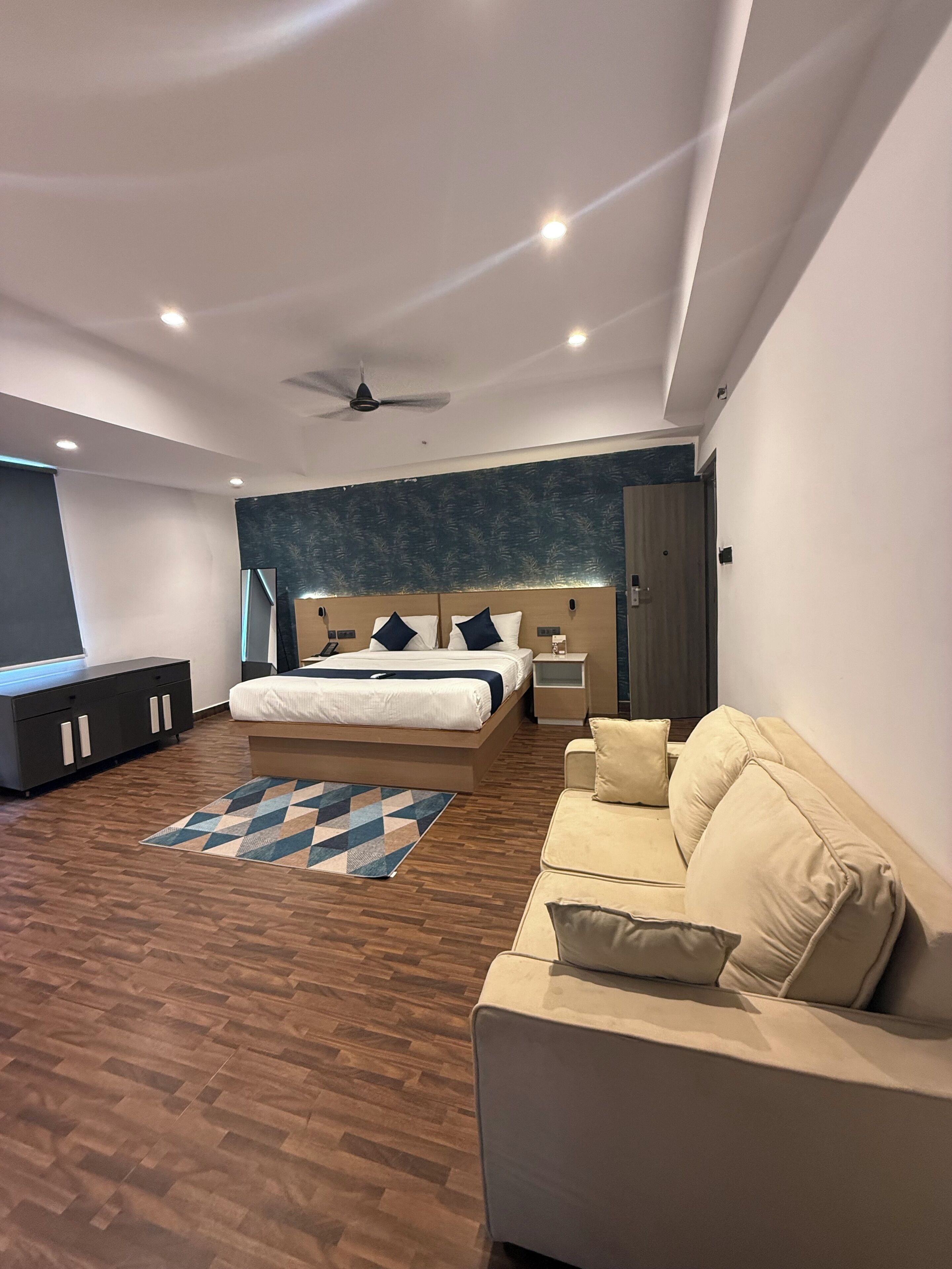 A modern bedroom with a bed, a sofa, a desk, and a ceiling fan.