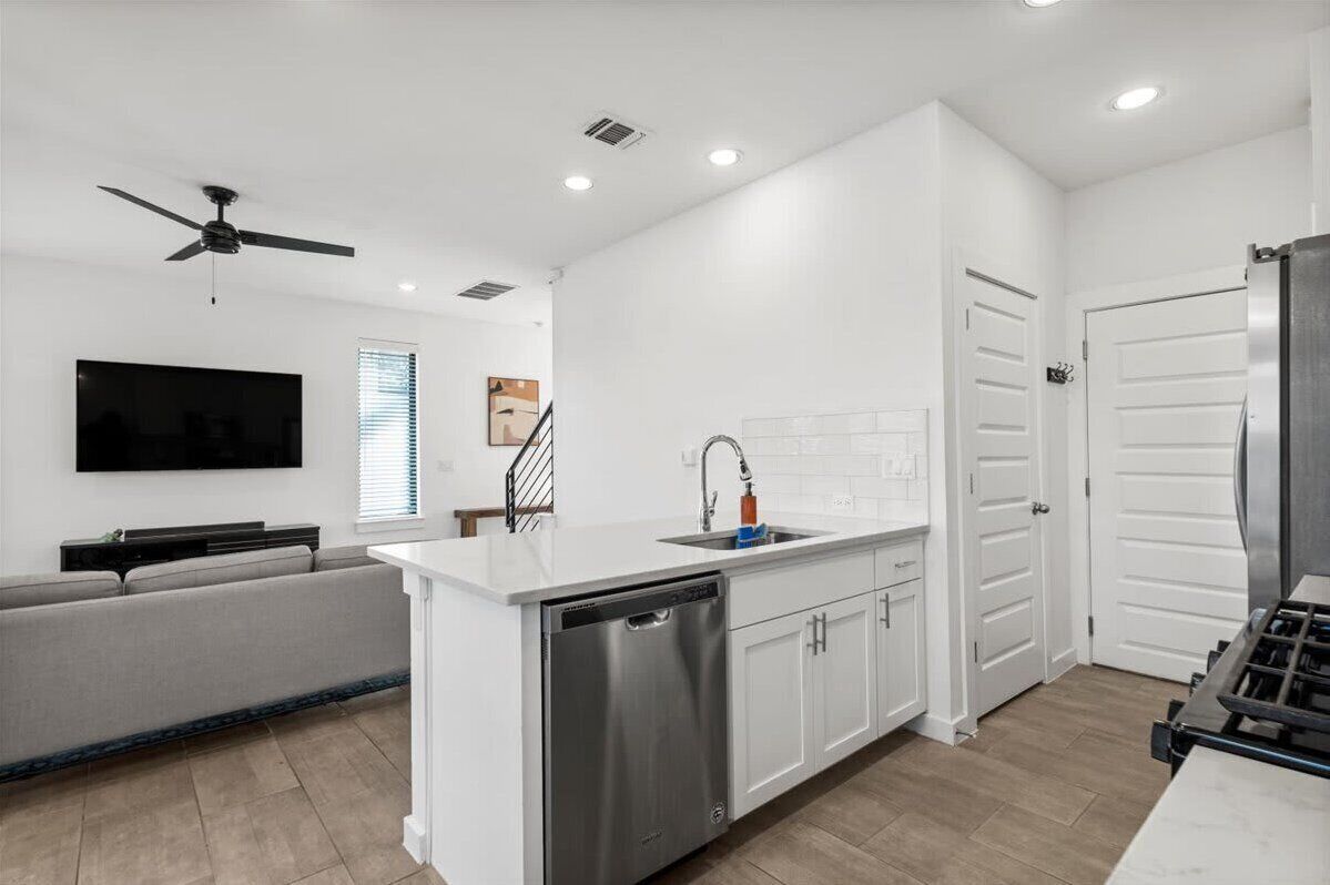 A modern kitchen with white cabinetry, a built-in dishwasher, and a gas stove.