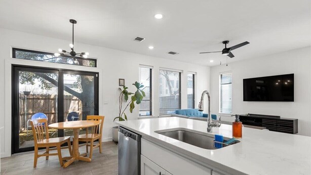 A modern kitchen with a large island, built-in appliances, and a dining area with wooden chairs.