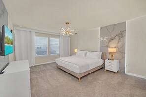 Ein Schlafzimmer mit Bett, Nachttisch, Lampe und einem Fernseher auf einem Schrank.