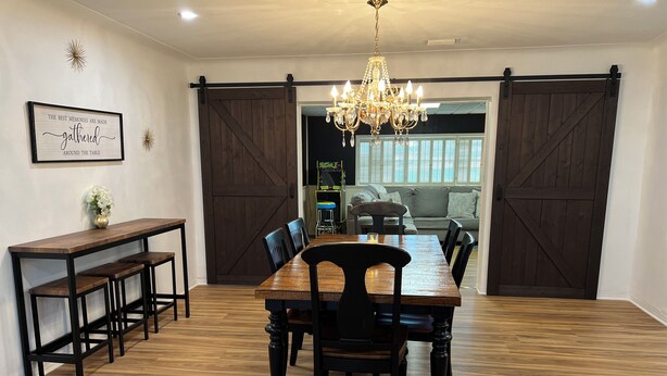 Un espace repas avec une table et des chaises en bois, un lustre et une porte coulissante de style rustique.