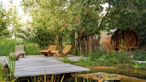 Een houten terras met twee ligstoelen en een kleine vijver met waterlelies.