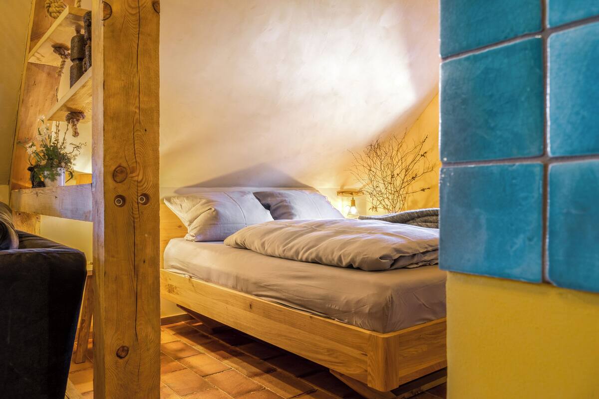 Un dormitorio acogedor con una cama de madera, una mesita de noche pequeña y una estantería con adornos.
