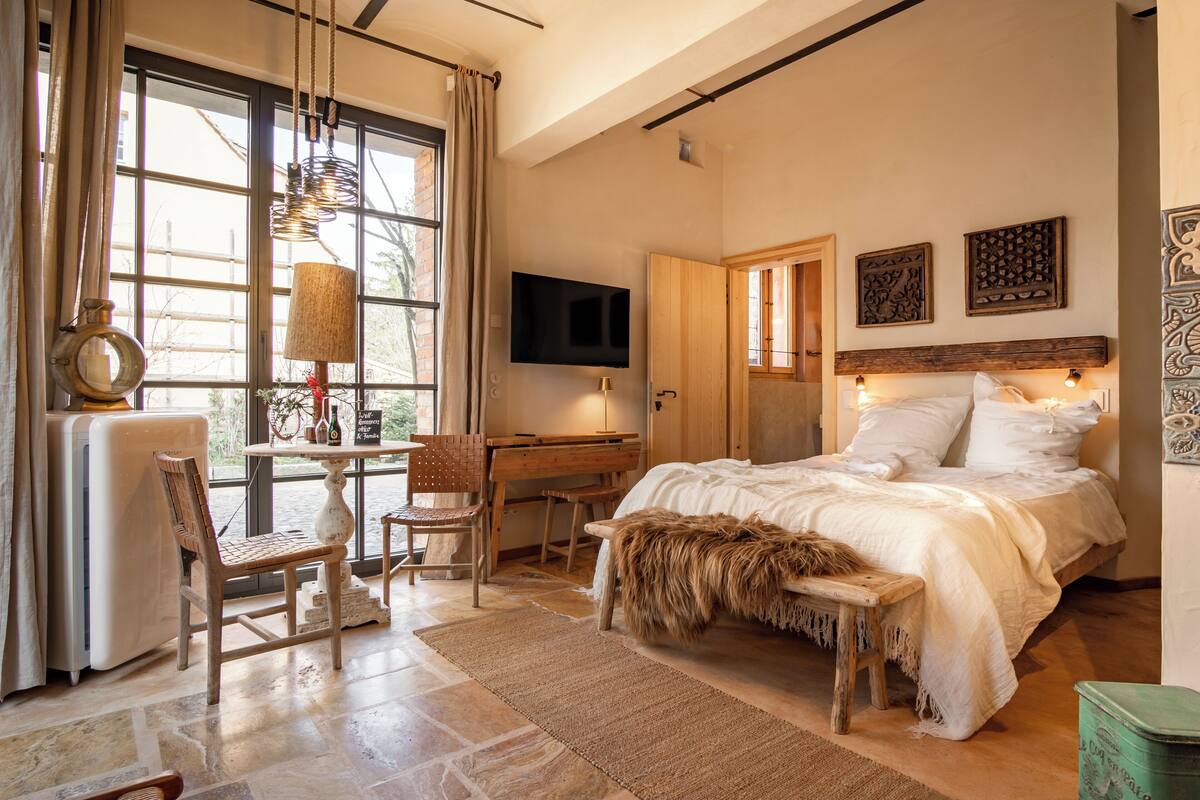 Un dormitorio con una cama grande, un escritorio, una silla, un televisor y una ventana con cortinas.
