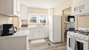Una cocina moderna con armarios blancos, estufa integrada y refrigerador.
