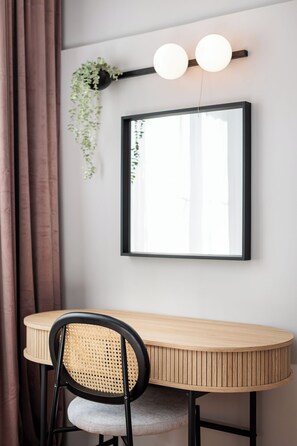 Un comedor con una mesa redonda de madera, una silla negra con asiento de mimbre y un cuadro enmarcado en la pared.