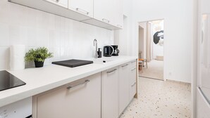 A modern kitchen with white cabinets, a black countertop, and a coffee maker. - Retro Glamour by Upstairs (Kraków)