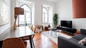 A modern living room with a dining area, large windows, a flat-screen TV, and a fireplace. - Rosemary Apartment, Campo de Ourique, Lisbon (Lisboa)