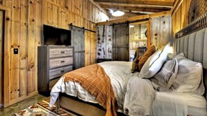 Un intérieur en bois comprenant un lit, un téléviseur et une commode.