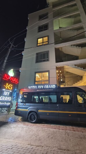 Monikerroksinen rakennus, jossa on kyltti, jossa lukee ”Hotel Ivy Grand”, ja jonka edessä on pysäköitynä bussi.