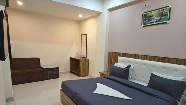 A bedroom with a large bed, a nightstand, a dresser, and a mirror. - HOTEL LA PLAZO (Haridwar)