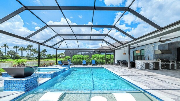 A covered outdoor swimming pool with a patio area, a barbecue, and a view of the surrounding landscape. - Esplanade by the Islands (Naples)