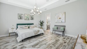 A bedroom with a bed, nightstands, a bench, and artwork on the walls. - Esplanade by the Islands (Naples)