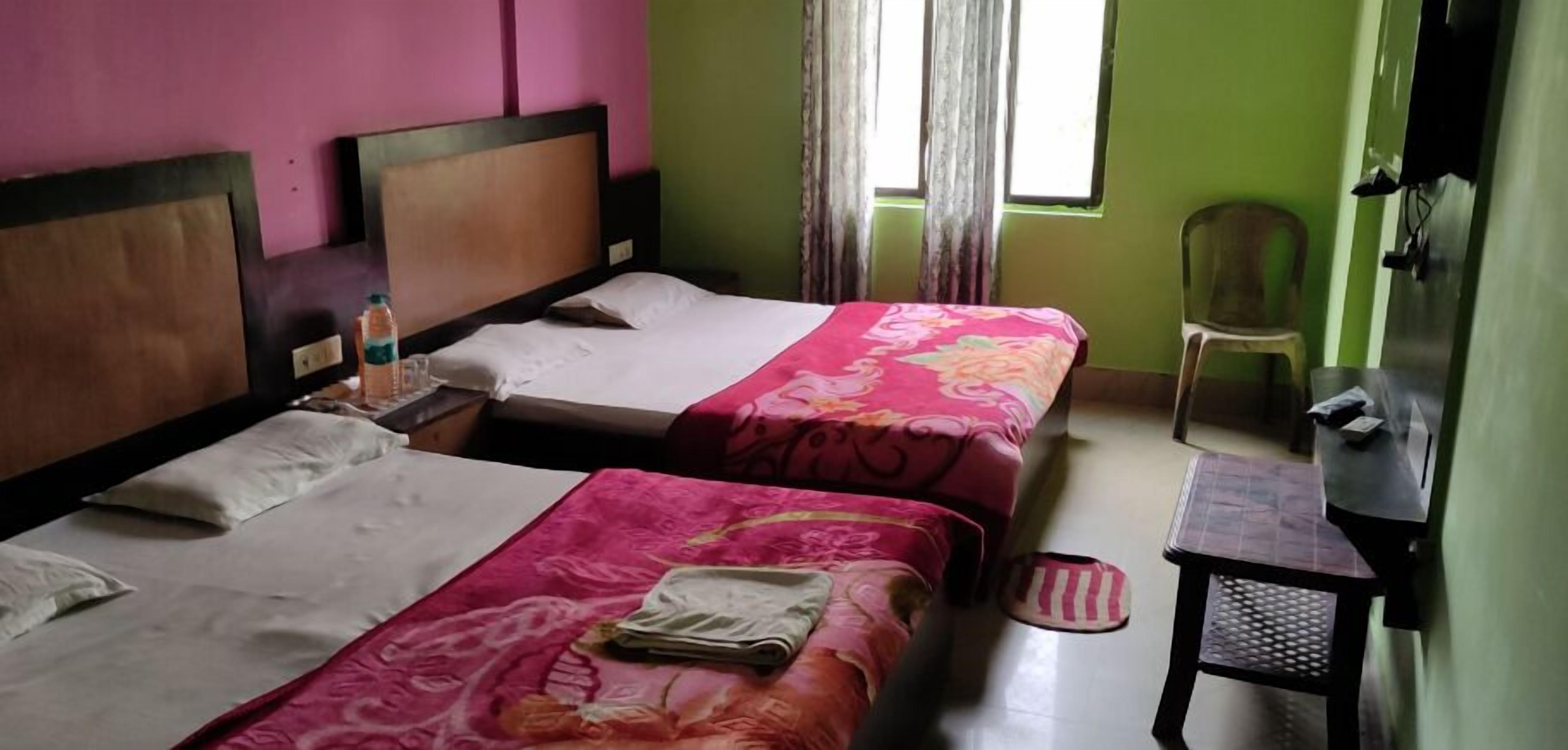 A hotel room with two beds, a chair, a small table, and a TV.