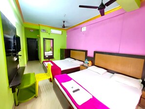 Habitación de hotel con dos camas, televisor, ventilador de techo y espejo.