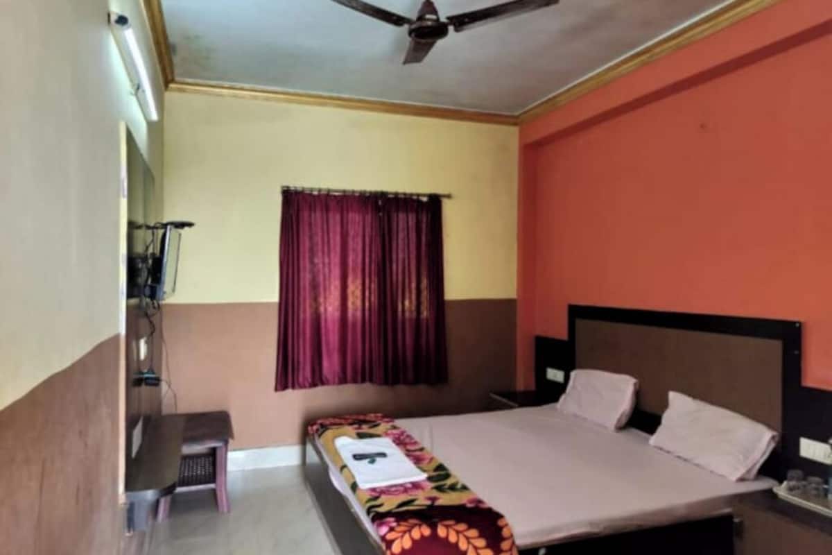 A bedroom with a bed, a ceiling fan, a window with curtains, and a bedside table.