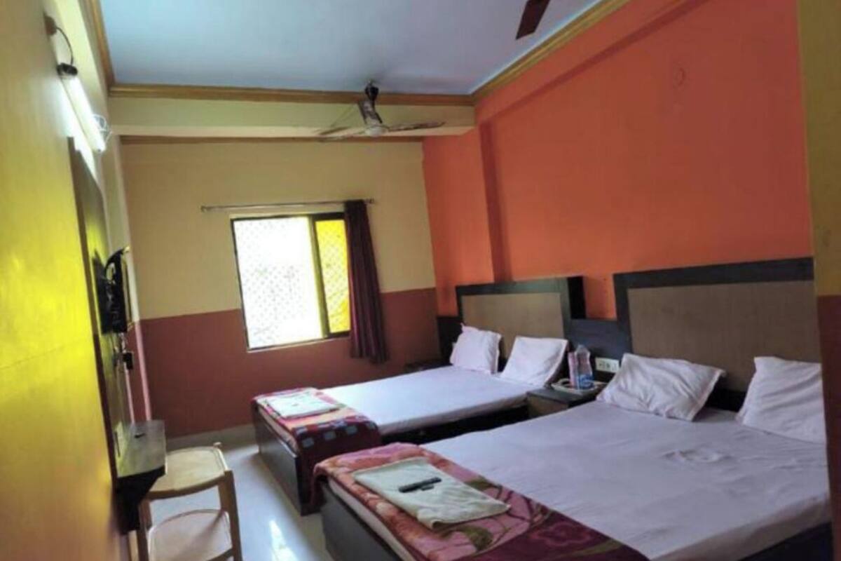 A hotel room with two beds, a desk, a chair, and a window with curtains.