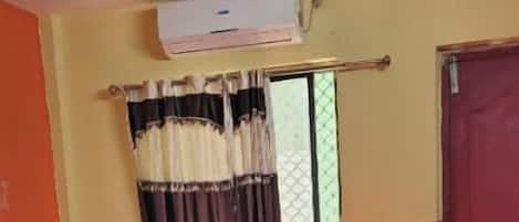Una camera da letto con un letto, una finestra con tende, una porta e un condizionatore d'aria.