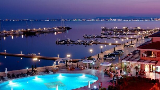 A marina at dusk with boats docked, a swimming pool, and a restaurant area. - Sea Vista Hotel (Sveti Vlas)