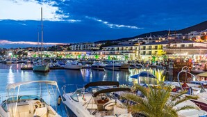 A marina with boats docked, a waterfront promenade, and buildings with illuminated signs. - Sea Vista Hotel (Sveti Vlas)