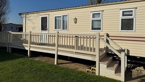 A single-story mobile home with a front porch, a small deck, and a covered outdoor area. - Family Caravan - Sleeps 6 - Pets Allowed - Pool (King's Lynn)