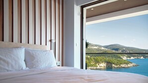 Un dormitorio con una cama grande, listones de madera en la pared y vistas a un paisaje costero.