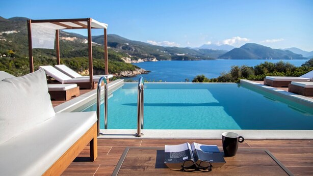 Un área junto a la piscina con terraza de madera, sillas de descanso y una pérgola.