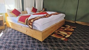 Ein Holzbett mit weißer Bettwäsche und roten Kissen in einem Zimmer mit grüner Wand und gemustertem Teppich.