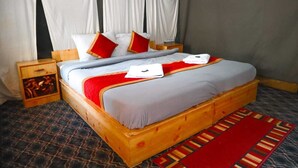 Ein Bett mit Holzrahmen, weißer Bettwäsche, roten Kissen und einem Teppich mit roten und goldenen Streifen.