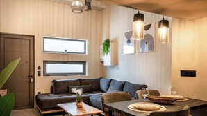 Una sala de estar moderna con un sofá modular, una mesa de comedor con sillas e iluminación colgante.
