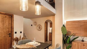 Un comedor con una mesa de mármol, dos sillas, una lámpara colgante y un armario de madera.