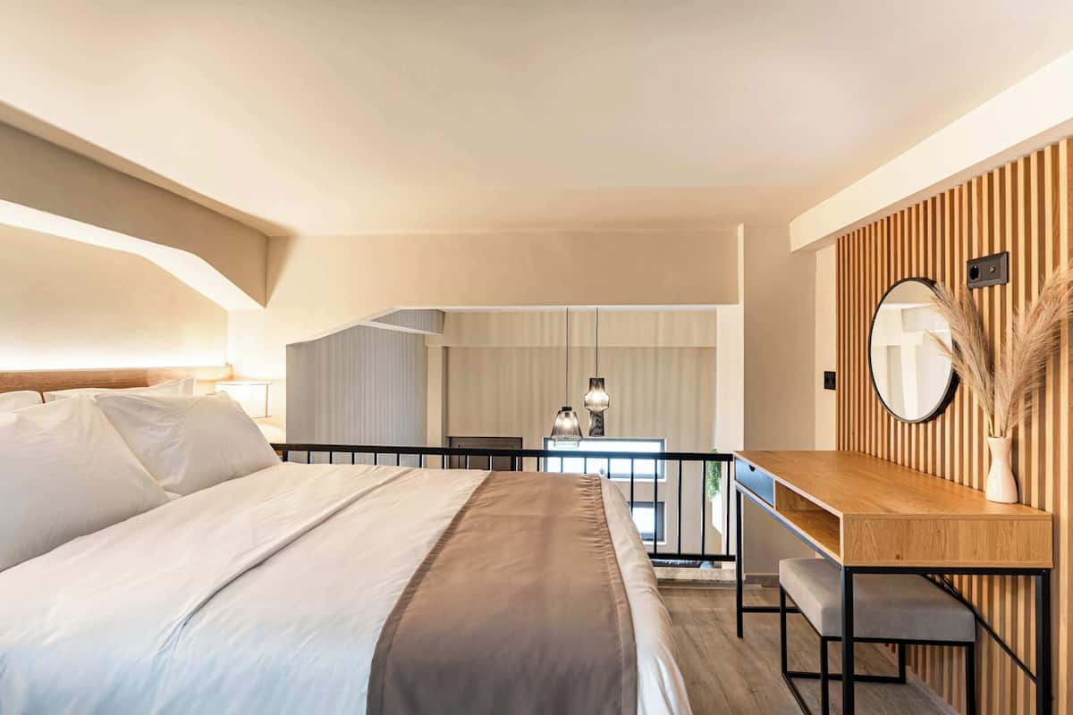 Un dormitorio moderno con una cama grande, un escritorio de madera y un espejo.