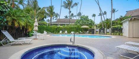 A swimming pool with lounge chairs and palm trees in the background.