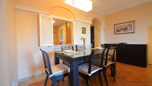 A dining area with a rectangular table, six chairs, and a vase with flowers. - LOS CISNES 296 - Three Bedroom Apartment, Sleeps 7 (Punta del moral)