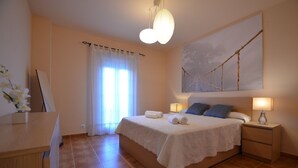 A bedroom with a bed, bedside tables, a desk, and a window with curtains. - LOS CISNES 296 - Three Bedroom Apartment, Sleeps 7 (Punta del moral)